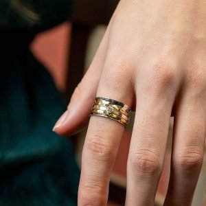 Sterling silver spinning ring with hammered surface and triple moving bands, one silver with a cut gemstone and two brass