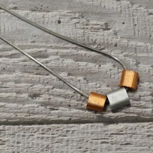 A necklace with buttery copper and matt aluminium tubes strung on a striking 18 inch stainless steel chain