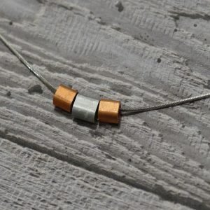 A necklace with buttery copper and matt aluminium tubes strung on a striking 18 inch stainless steel chain